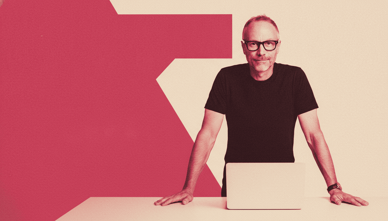 Falk Gottlob leaning on a standing desk with a laptop open, looking straight at the camera, rendered as a rose duotone.
